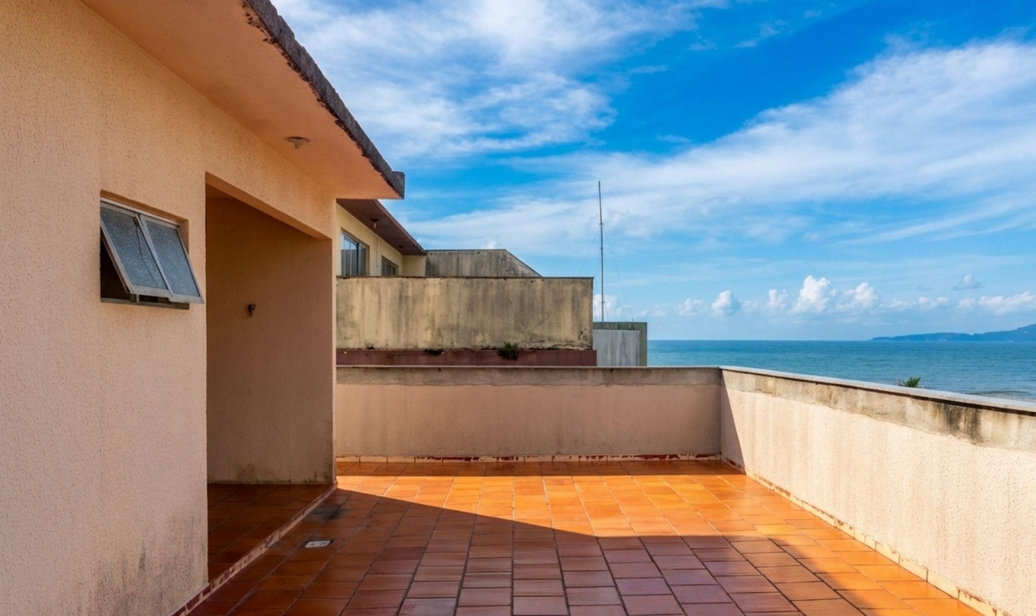 A rooftop terrace with a view of the sea and distant mountains.