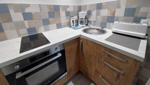 Una cocina compacta con horno integrado, cafetera y tostadora sobre la encimera.