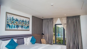 Ein modernes Hotelzimmer mit einem großen Bett, einem Stadtbildgemälde, Blick ins Grüne und einer Schiebetür aus Glas.