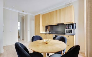 Une cuisine moderne avec des meubles en bois, une table de salle à manger ronde et des chaises noires.