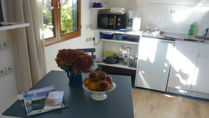 A compact kitchen with a dining table, a microwave, and a refrigerator. - "Chestnut, between land and sea (Plouézec)