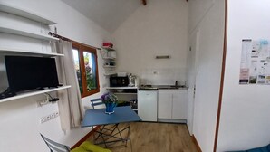 A compact kitchen with a dining area, a television, and a small refrigerator. - "Chestnut, between land and sea (Plouézec)