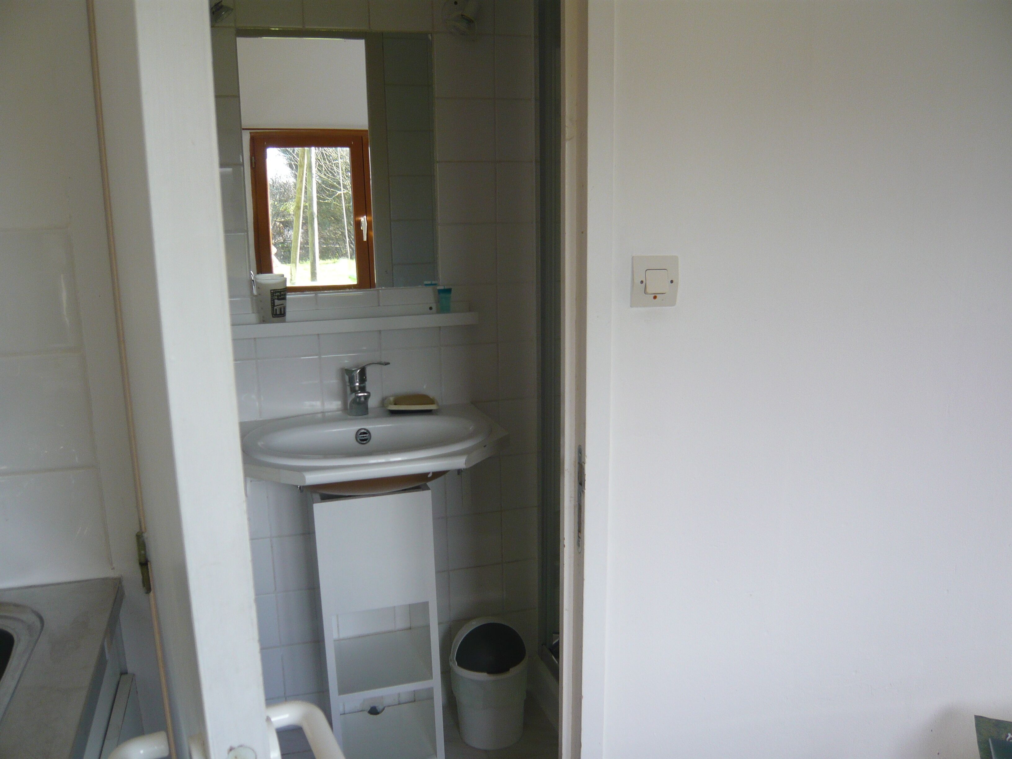 A bathroom with a white sink, mirror, and a window above the mirror.