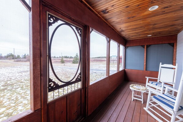 Een houten veranda met uitzicht op een besneeerd landschap.
