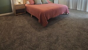 A bedroom with a bed, nightstands, a ceiling fan, and a mirror. - Medical Oasis - 2 Kings, 1 Queen - Work desk (Lubbock)