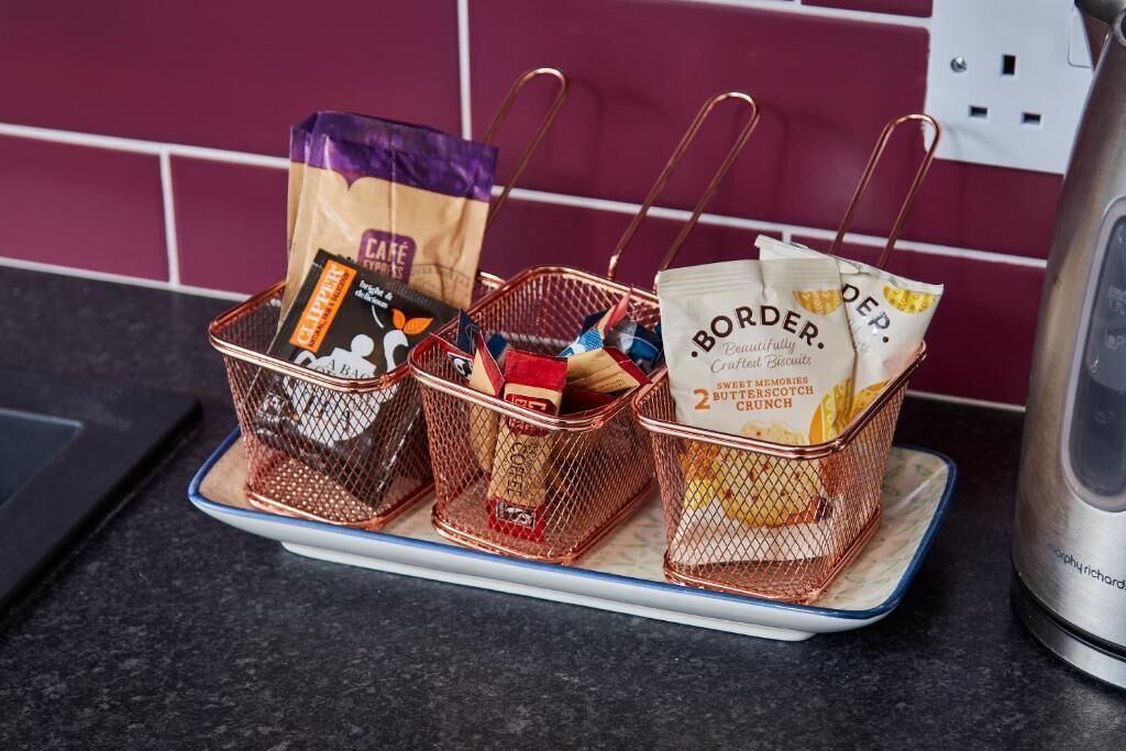 Three wire baskets on a tray with various packaged food items.