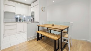Uma cozinha moderna com armários brancos, uma mesa de jantar de madeira e uma cadeira branca.