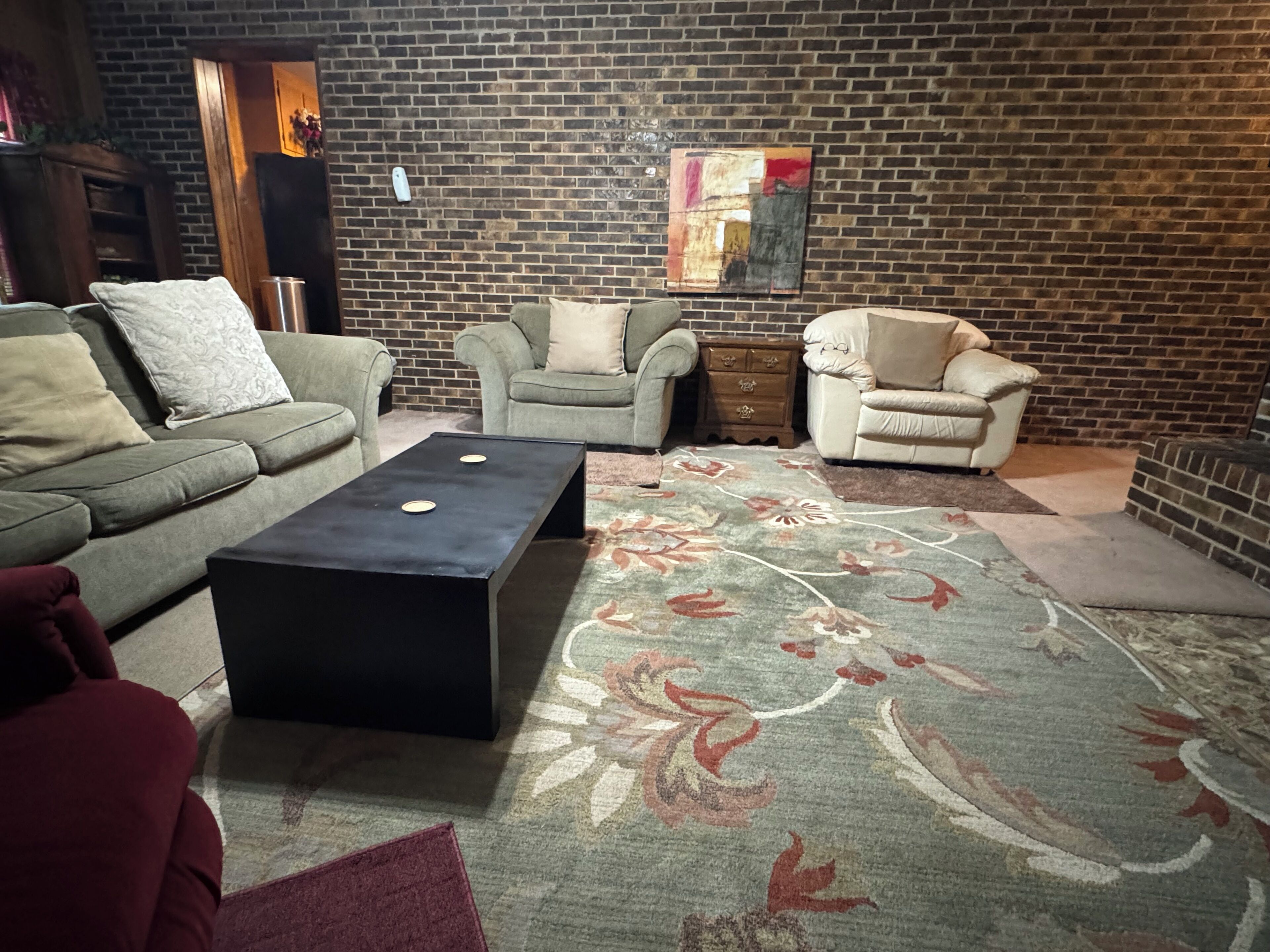 Un salon avec un mur en briques, deux canapés, une table basse et un tapis à motifs.