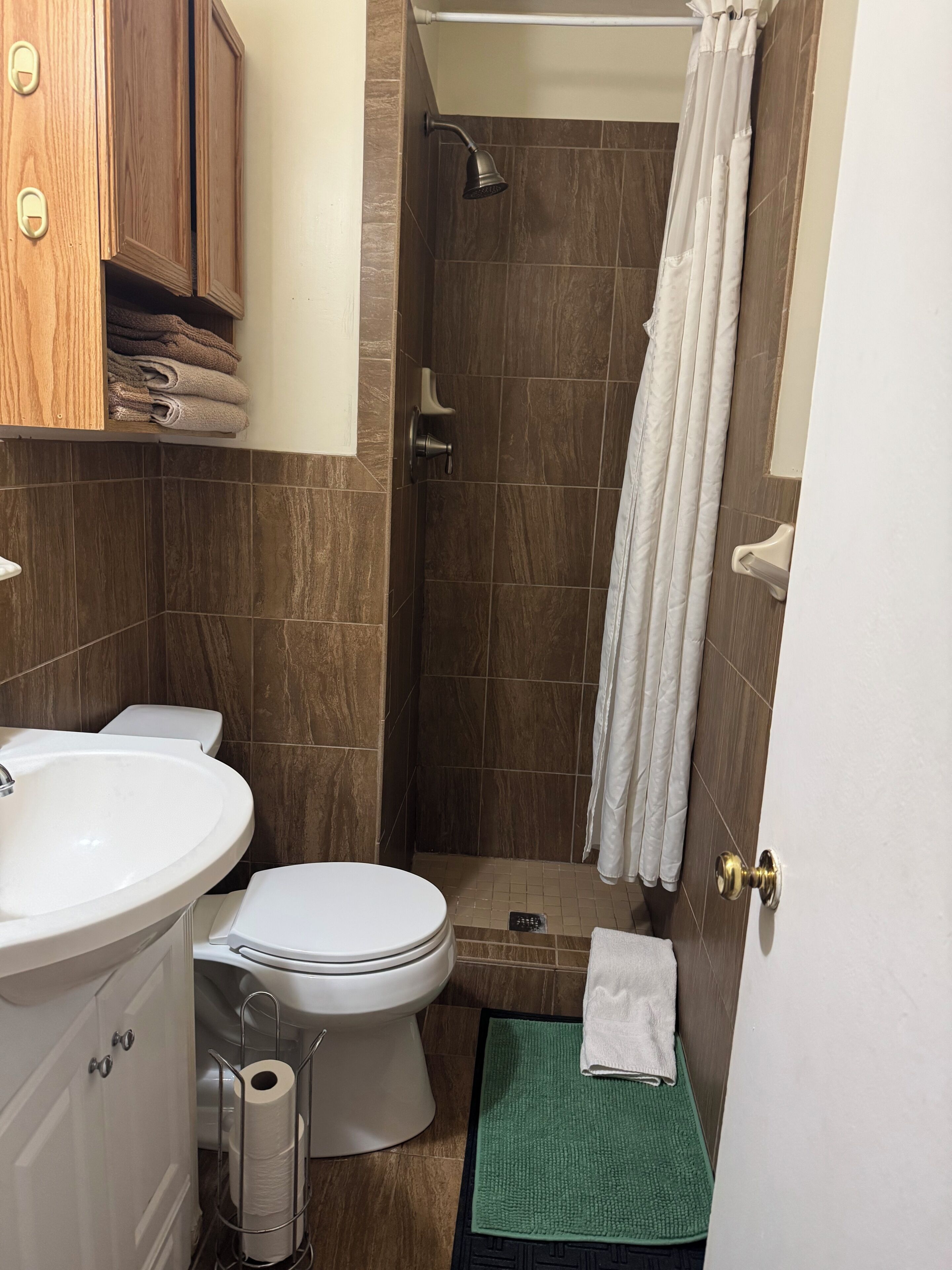 A bathroom with a toilet, sink, shower, and a towel rack.