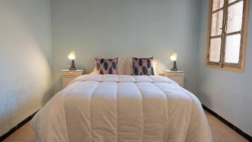 A bedroom with a bed, two bedside tables, and a window.