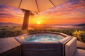 Un bain à remous offrant une vue sur un coucher de soleil se déclinant sur un paysage.