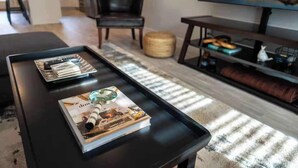 A modern living room with a black coffee table, a magazine, and a remote control. - All king beds, bike garage, Near Back 40 (Bella Vista)