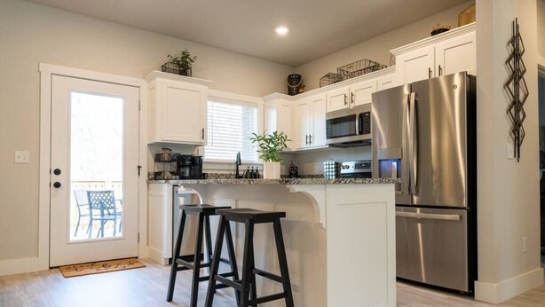 A modern kitchen with white cabinets, stainless steel appliances, and a wooden island with bar stools. - All king beds, bike garage, Near Back 40 (Bella Vista)
