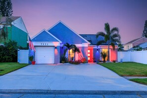 A residential house with a garage, a front yard, and a driveway. - Heated Pool & Spa, 9 Mins to Beach, Golf, Raymond James Stadium Sleeps 8  (Largo)