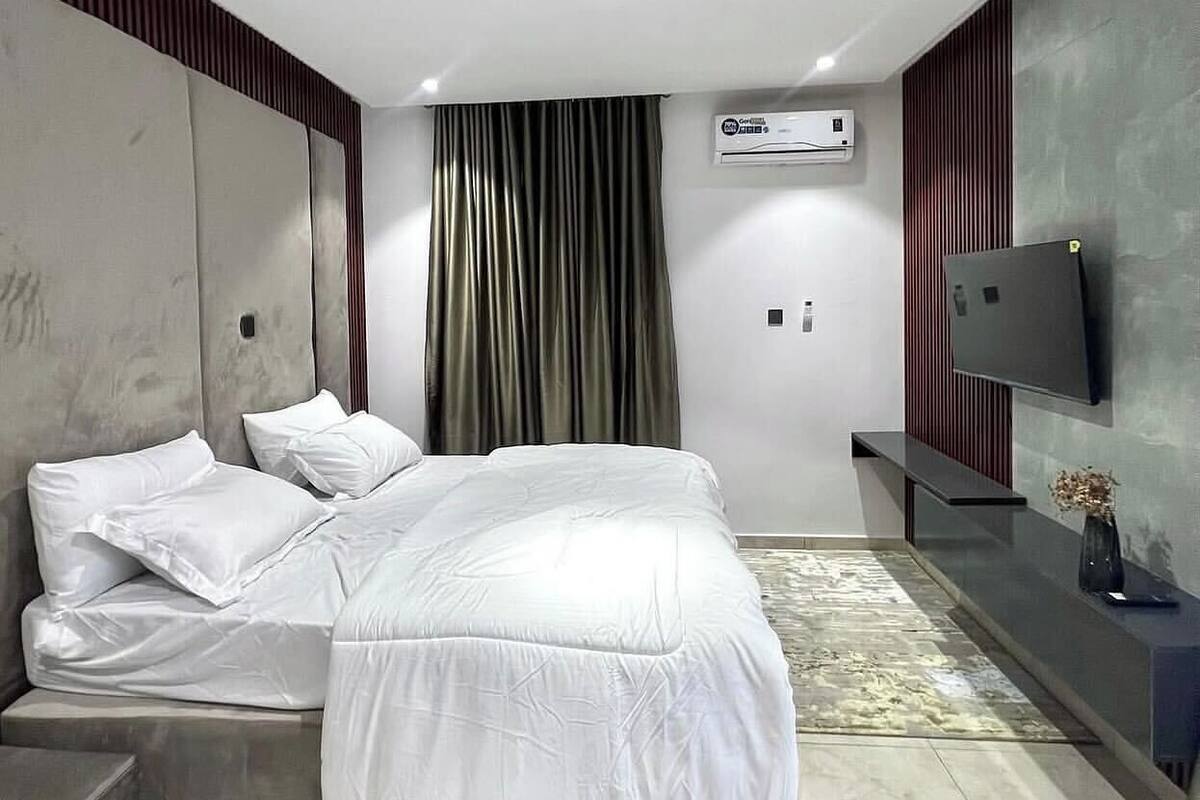 Una camera da letto moderna con un letto, una TV a schermo piatto e un condizionatore d'aria.