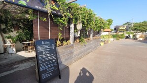 En restaurant med udendørs siddepladser, en træfacade og et skilt med menuer.