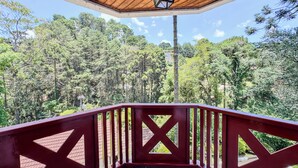 A wooden deck with red railings overlooking a forested area. - Apê Bosque do Silêncio (Campos do Jordão)