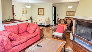A living room with a red sofa, a fireplace, and a dining area. - Apê Bosque do Silêncio (Campos do Jordão)