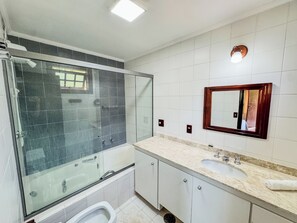 Ein modernes Badezimmer mit einer Duschkabine, einem Waschbecken mit Ablagefläche und einem Spiegel an der Wand.