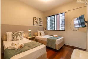 A hotel room with two beds, a TV, a window with a view, and a bedside table with a lamp. - Near Rodrigo de Freitas Lagoon | PC308 (Rio de Janeiro)