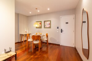 A dining area with a wooden table, chairs, and a hanging light fixture. - Near Rodrigo de Freitas Lagoon | PC308 (Rio de Janeiro)
