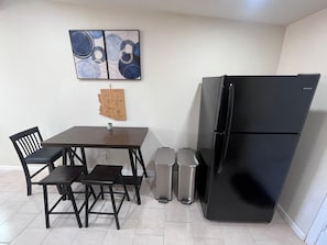 A compact kitchen with a black refrigerator, a wooden map wall hanging, and a small table with chairs. - Laguna Lounge - Private, Fully Stocked, Central, King bed, Washer/Dryer (Tucson)