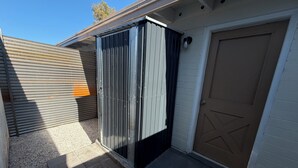 En garage med lukket metalport, en støbt indkørsel og en hvid bygning med en brun garageport.
