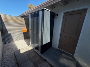 A garage with a closed metal door, a concrete driveway, and a white building with a brown garage door. - Laguna Lounge - Private, Fully Stocked, Central, King bed, Washer/Dryer (Tucson)