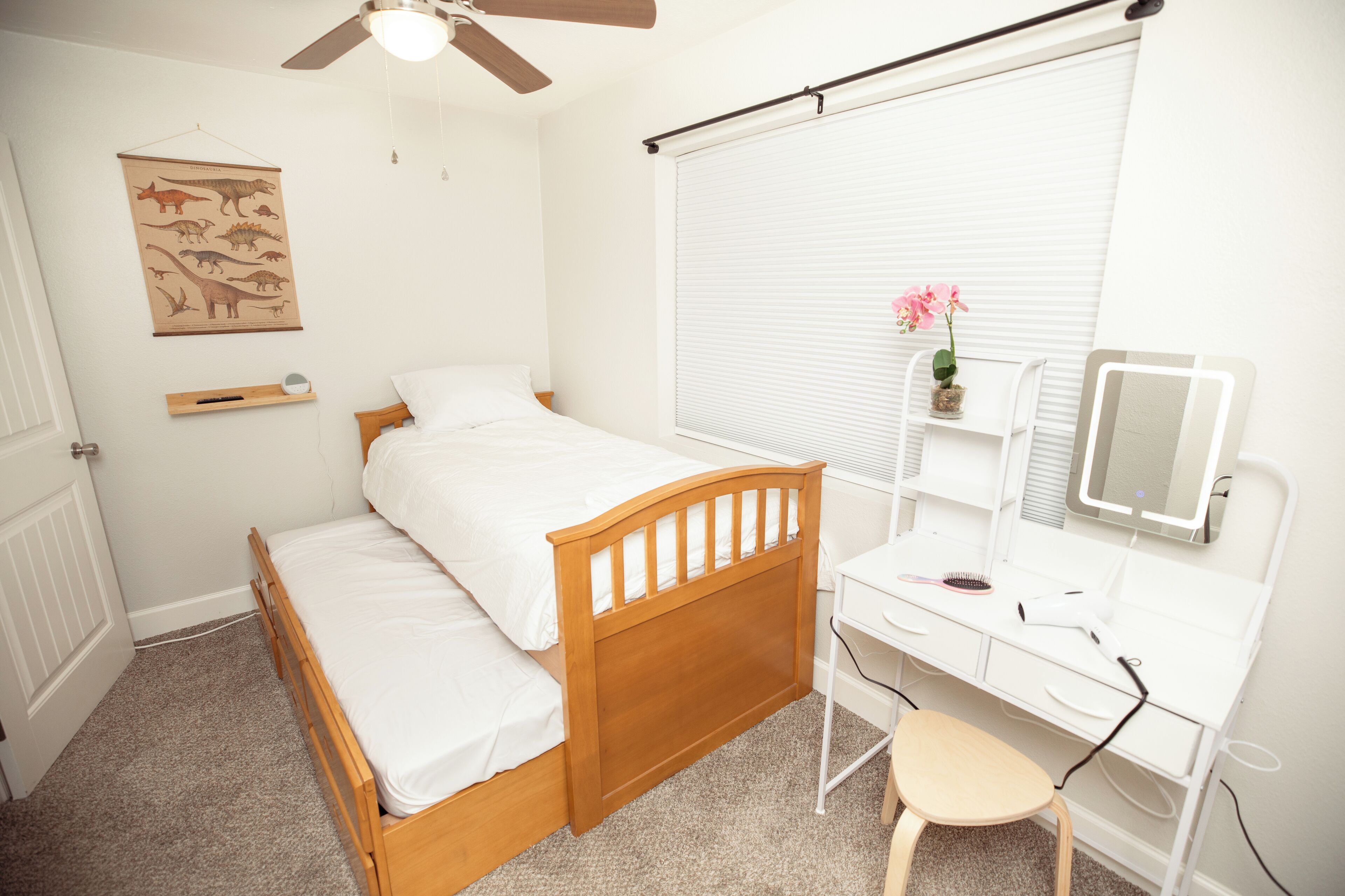 Une chambre à coucher avec un lit en bois, un bureau doté d’un miroir et une fenêtre avec des stores.