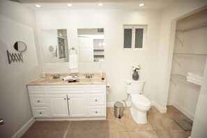 A modern bathroom with a vanity, sink, mirror, toilet, and shower area. - Fun Compound! EV charger, mini-golf, pool, B-ball, Work station, BBQ & Laundry (Tucson)