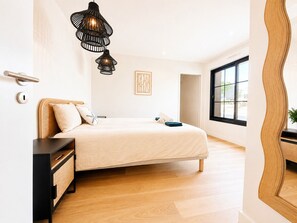 Un dormitorio con cama, mesitas de noche, un espejo y una ventana.