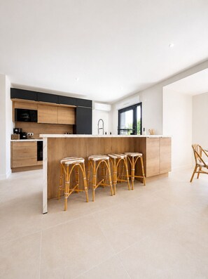 Una cocina moderna con una isla central, taburetes de bar y un área de comedor.