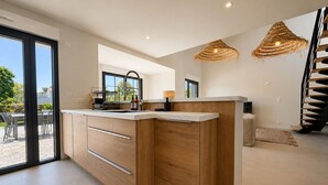 Eine moderne Küche mit Holzschränken, einer integrierten Kochinsel und einem Essbereich mit Tisch und Stühlen.
