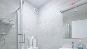 A modern bathroom with a glass shower enclosure, a white toilet, and a pedestal sink. - Flat in Bethnal Green (London)