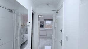 A hallway with white walls, a marble floor, and a ceiling light fixture. - Flat in Bethnal Green (London)