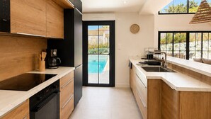Una cocina moderna con armarios de madera, un horno negro y un ventanal con vistas a una piscina.