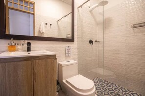 Ein modernes Badezimmer mit Duschkabine aus Glas, einer weißen Toilette und einem Waschbecken mit Holzausstattung.