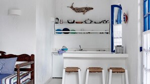 A compact kitchen with white walls, a wooden bed, and a blue-framed window. - White Blue Villa formerly Ippocampi (Hersonissos)