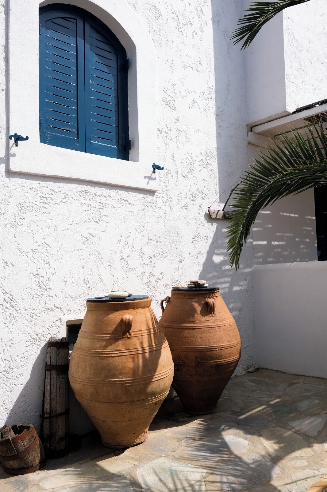 A white building with blue shutters and two large clay pots.
