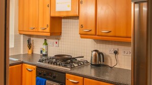 Uma cozinha compacta com armários de madeira, fogão a gás, forno e geladeira.
