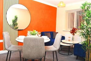 Un coin repas avec une table ronde, des chaises, un miroir et un canapé bleu.