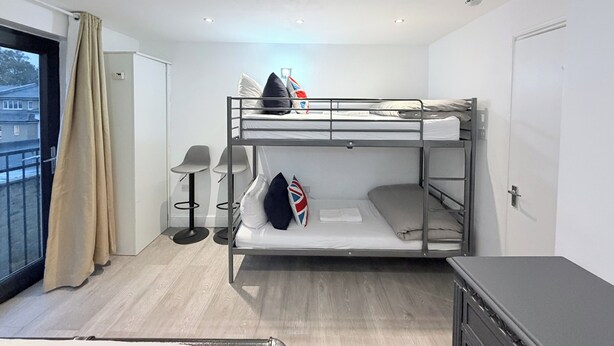 A bunk bed room with a view of buildings outside, a desk, and a chair. - Flat in Bethnal Green (London)