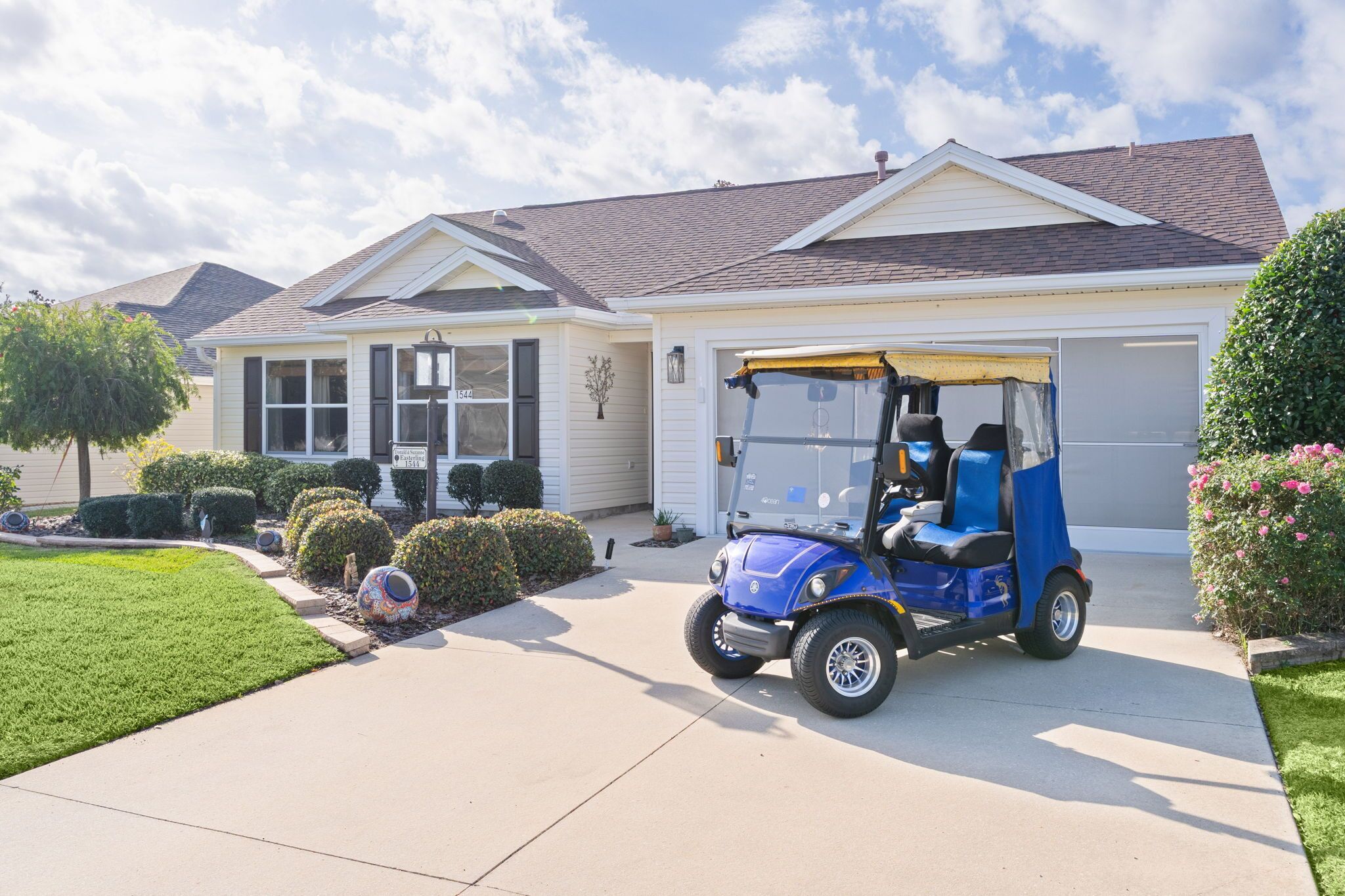 A residential house with a garage, a driveway, and a blue golf cart parked in front.