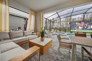 Ein modernes Wohnzimmer mit einer Eckcouch, einem Couchtisch und einem Fernsehbildschirm, der ein Sportspiel zeigt.