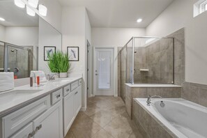 Une salle de bain moderne avec un grand miroir, une cabine de douche, une baignoire et une plante en pot.