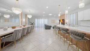Uma cozinha moderna com ilha central, banquetas e iluminação pendente.