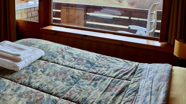 Een slaapkamer met een groot raam met uitzicht op een bergachtig landschap.