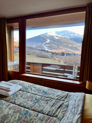 A bedroom with a large window offering a view of a mountainous landscape. - Alpine appartament with Mountain View_Bormio (Turri Piano)