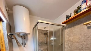 Een moderne badkamer met een douchecabine van glas, een wit wastafelmeubel en een toilet.