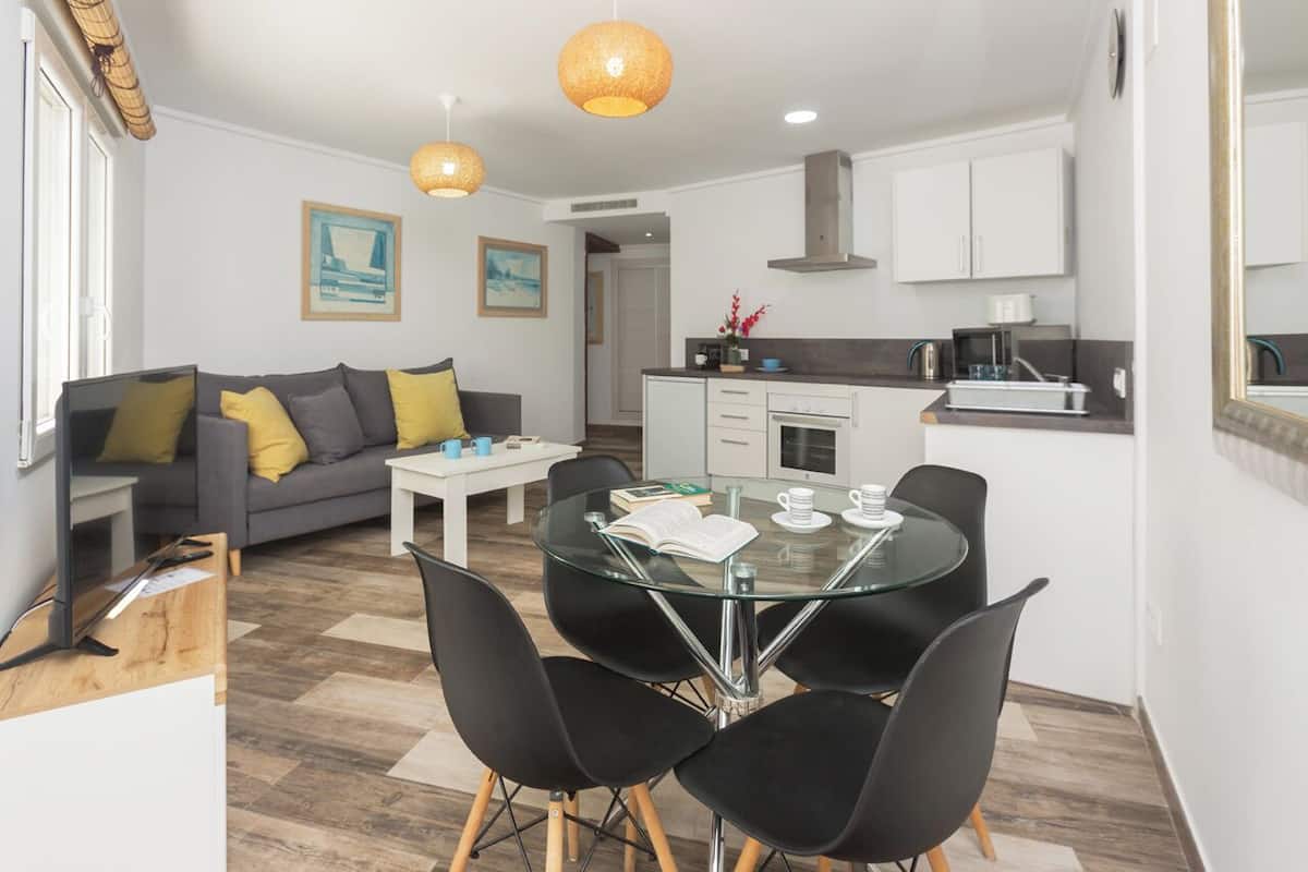 Un espacio de estar moderno con comedor, sofá y cocina.